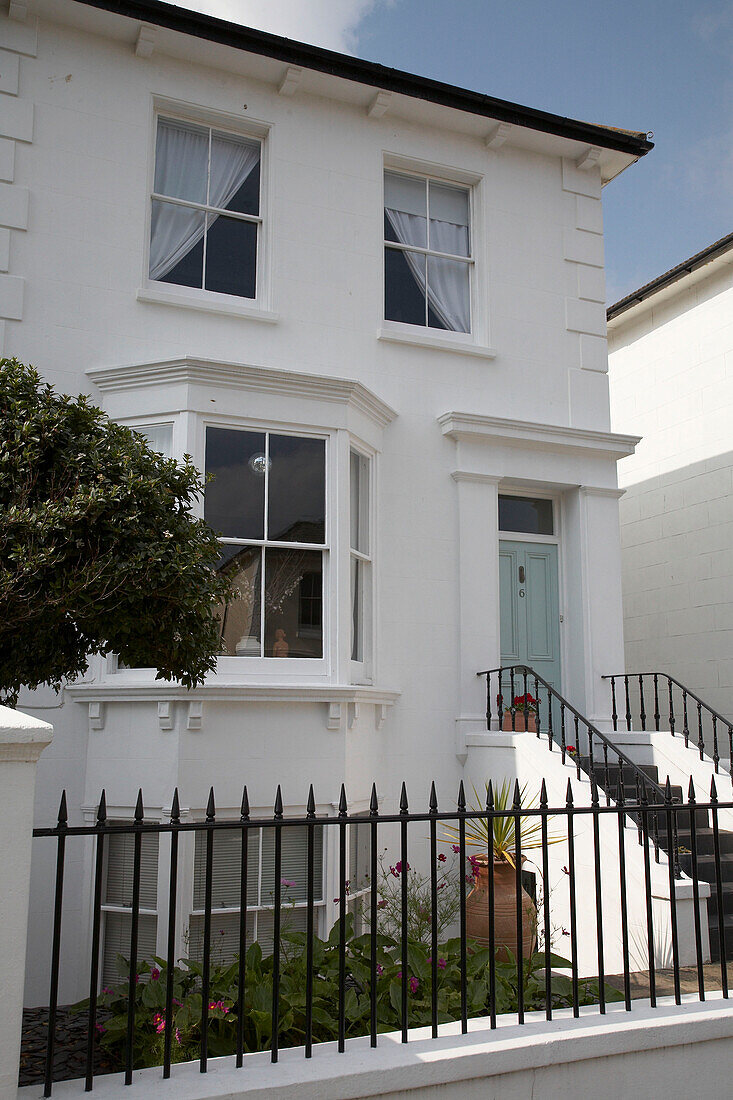 Exterior of whitewashed Victorian town house with bay windows