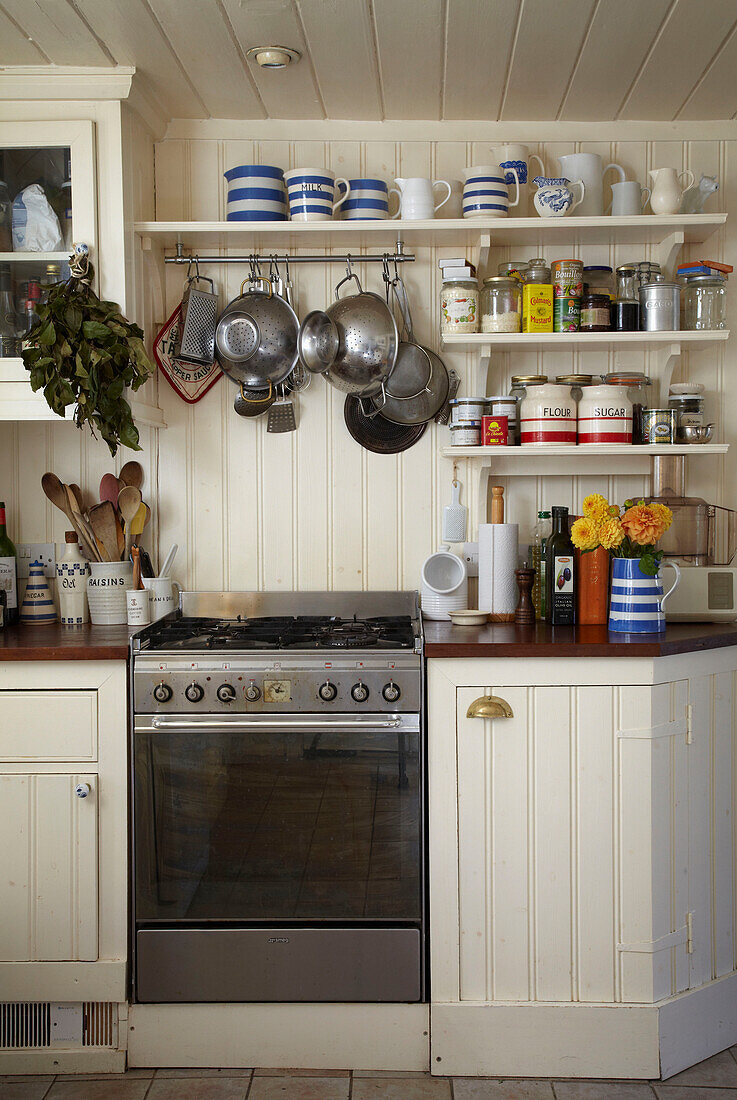 Panelled kitchen cupboards with oven and open shelving