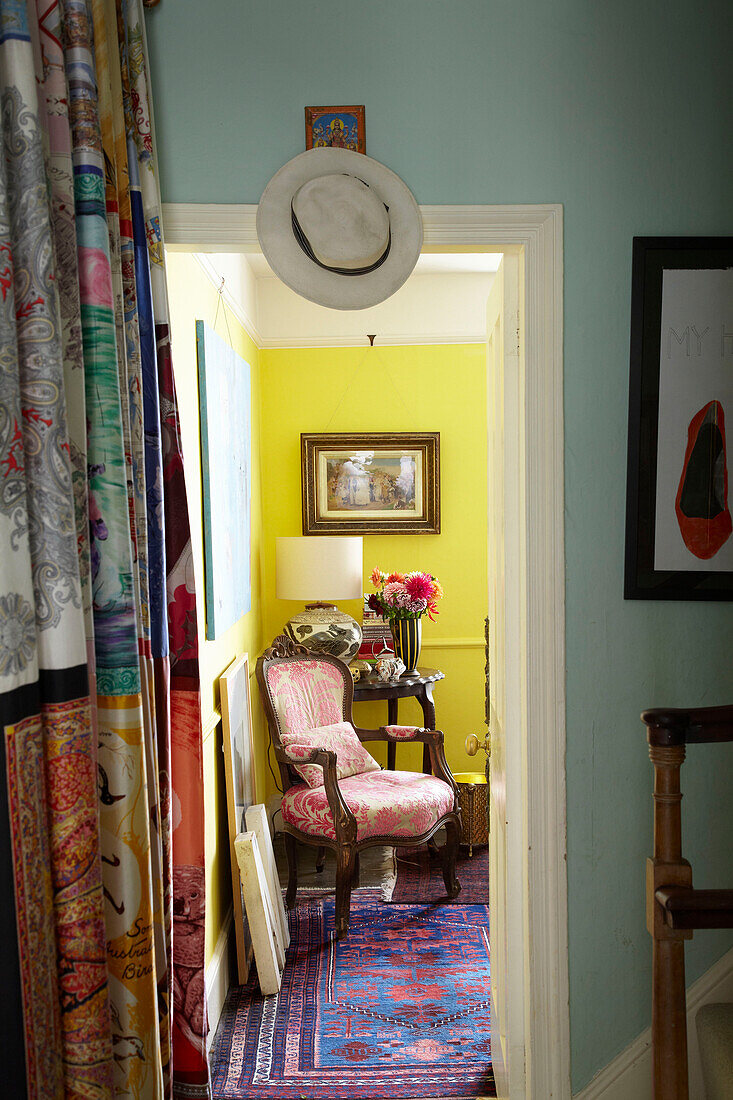 Mehrfarbiger Stoffvorhang und Blick durch die Tür in einen sonnendurchfluteten Raum