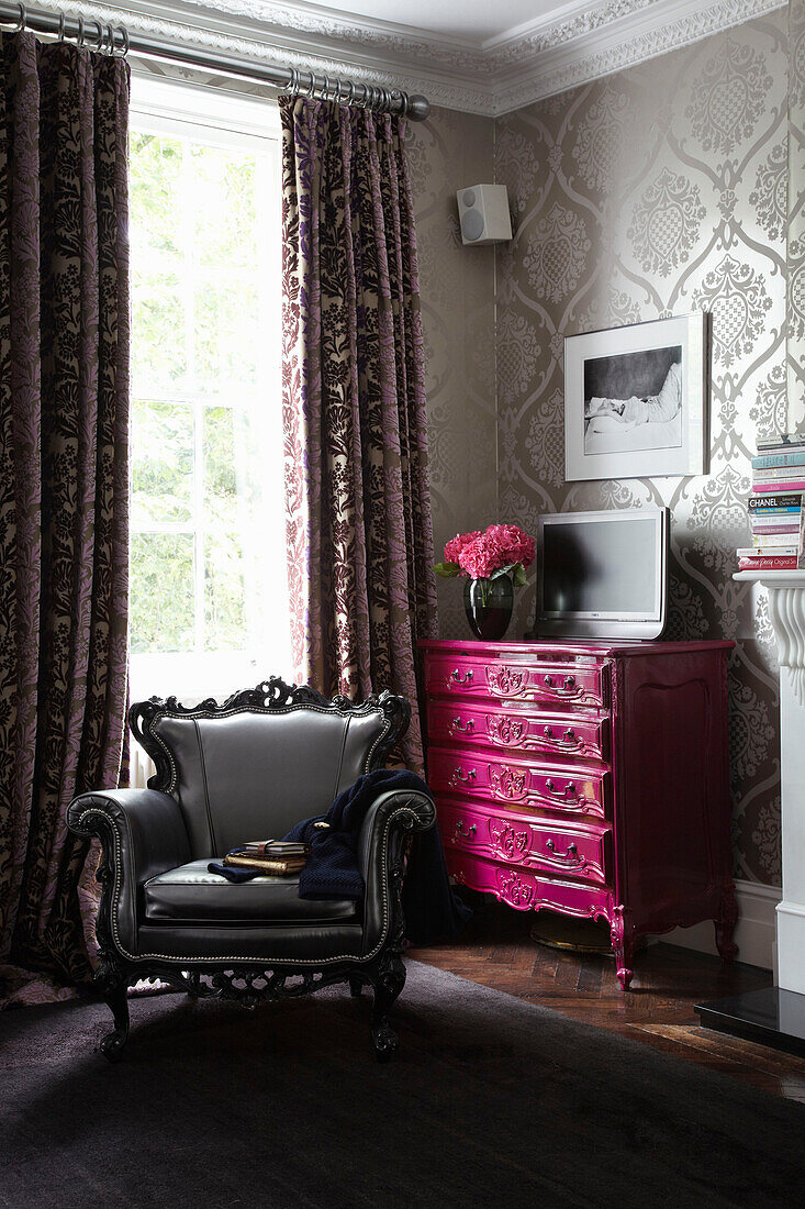 Rosa Kommode und grauer Sessel in einer Ecke des Hauses eines Londoner Modedesigners