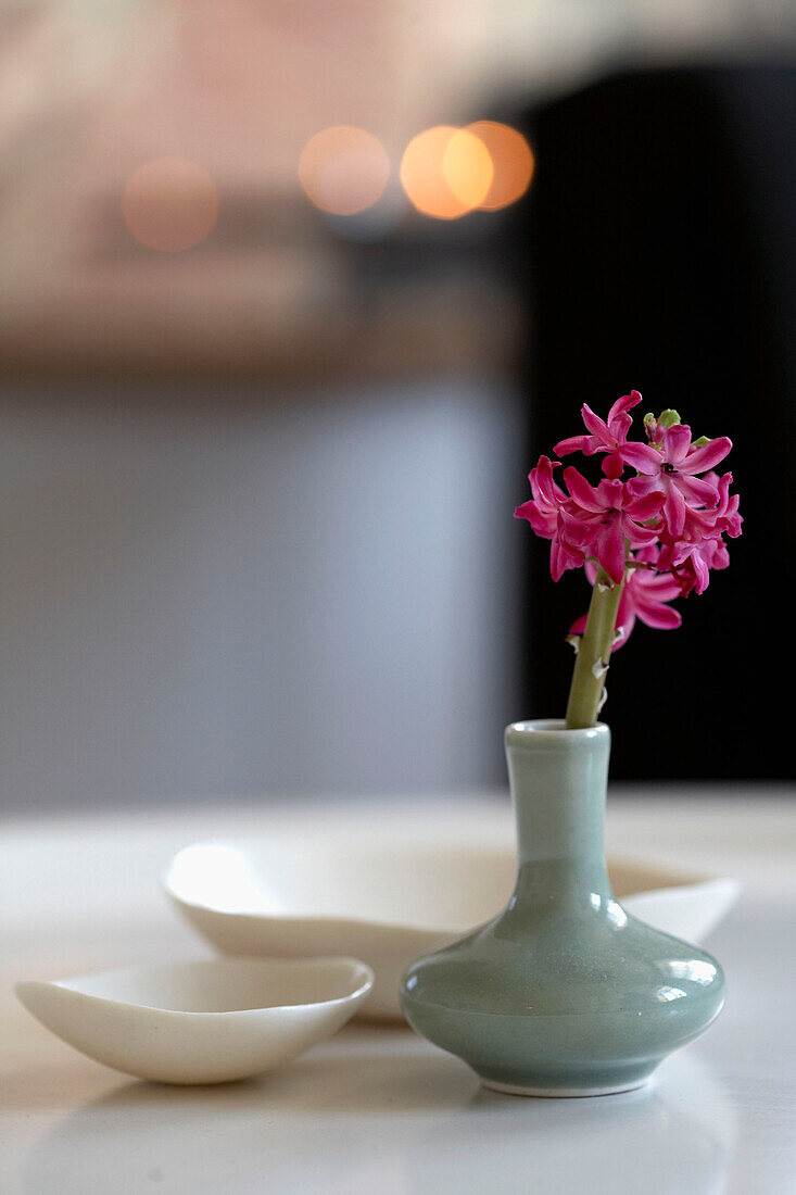 Lila Hyazinthe in kleiner Vase und dekorative Schalen auf dem Tisch, Nahaufnahme