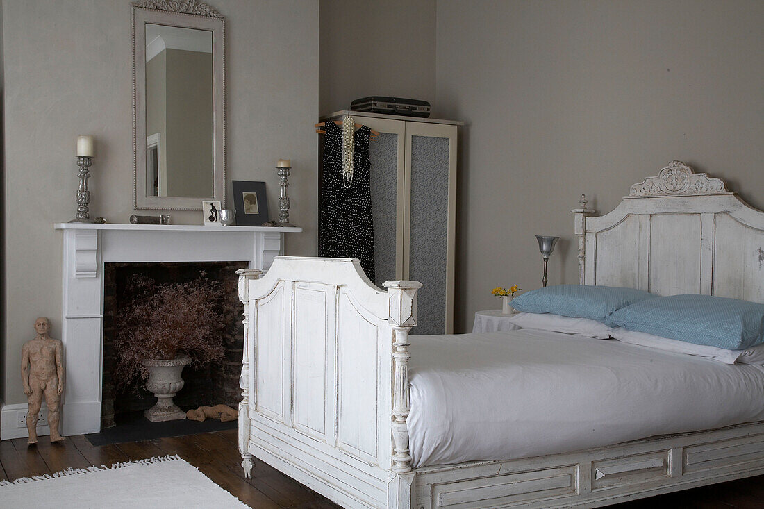 Double bed with carved wooden headboard next to fireplace
