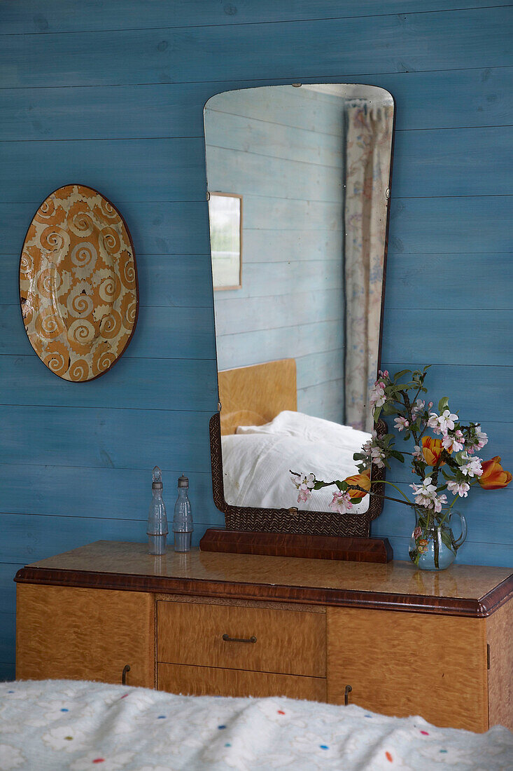 Spiegel über einem Schminktisch im Retrostil in einem blau gestrichenen Zimmer