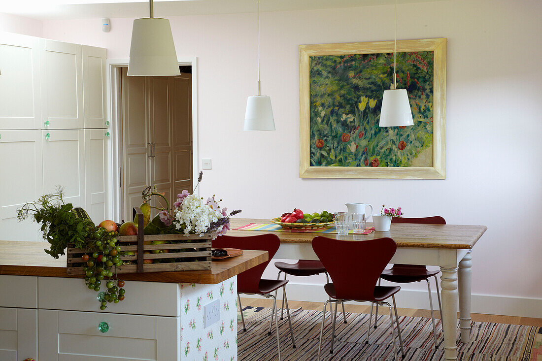 Pendant lights hang over wooden dining room table with vegetable box on worktop