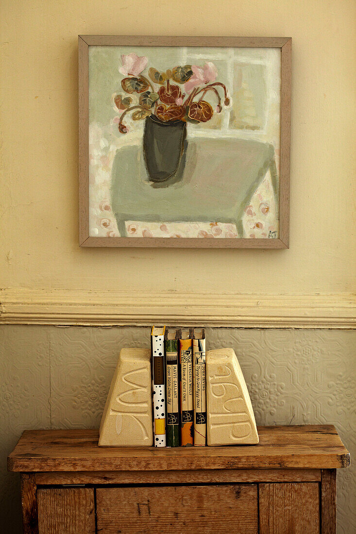 Bücher auf einem Beistelltisch unter einem Wandbild in einer Wohnung in Brighton, UK