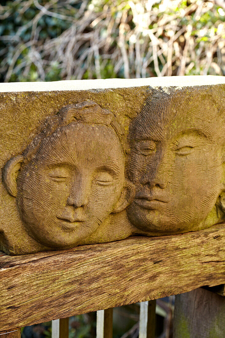 Steinrelief mit zwei Gesichtern im Garten, Brighton, Sussex, UK