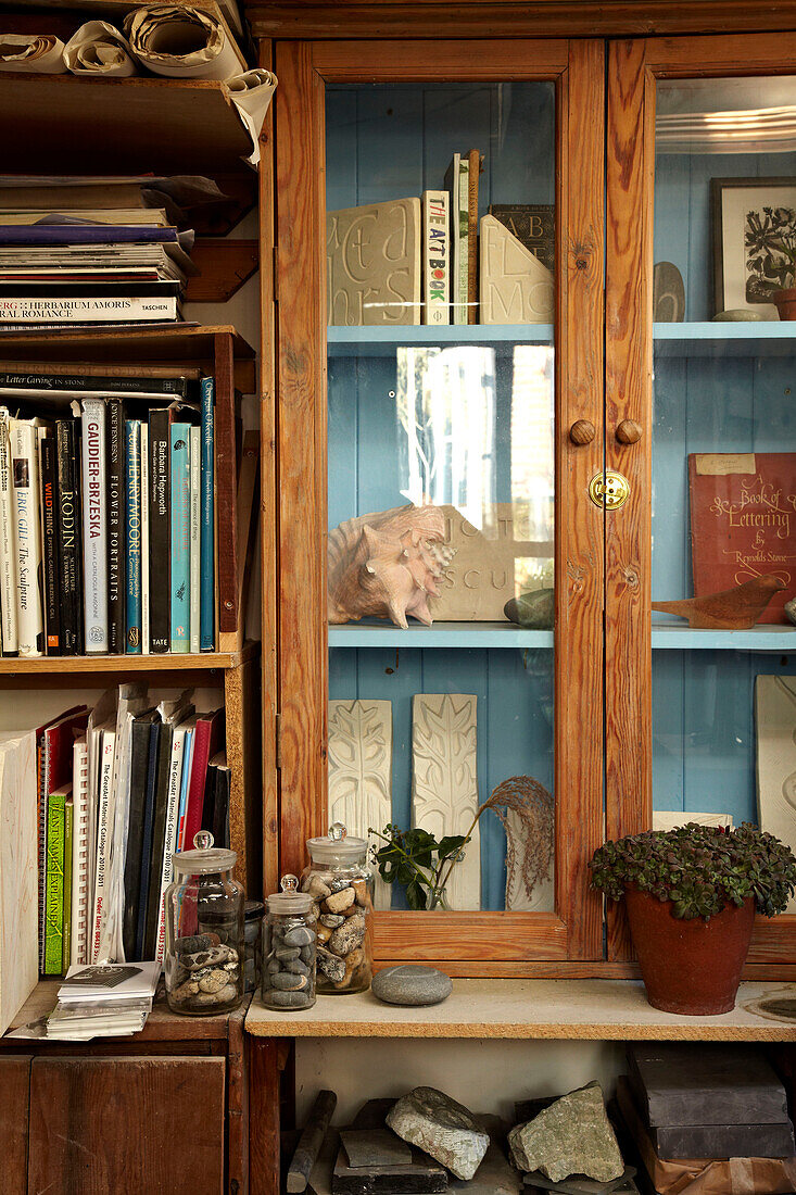 Bücherregal und Glasvitrine in einem Künstleratelier in Brighton, Sussex, UK