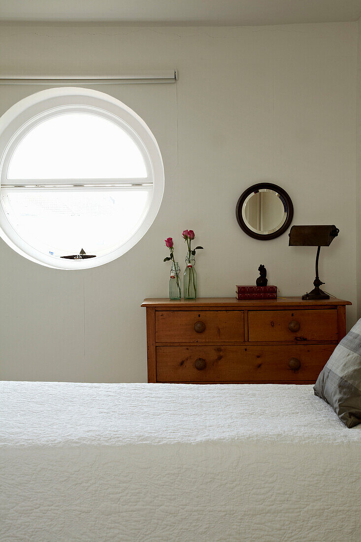 Circular porthole window with wooden chest of drawers in Brighton townhouse, Sussex, England, UK