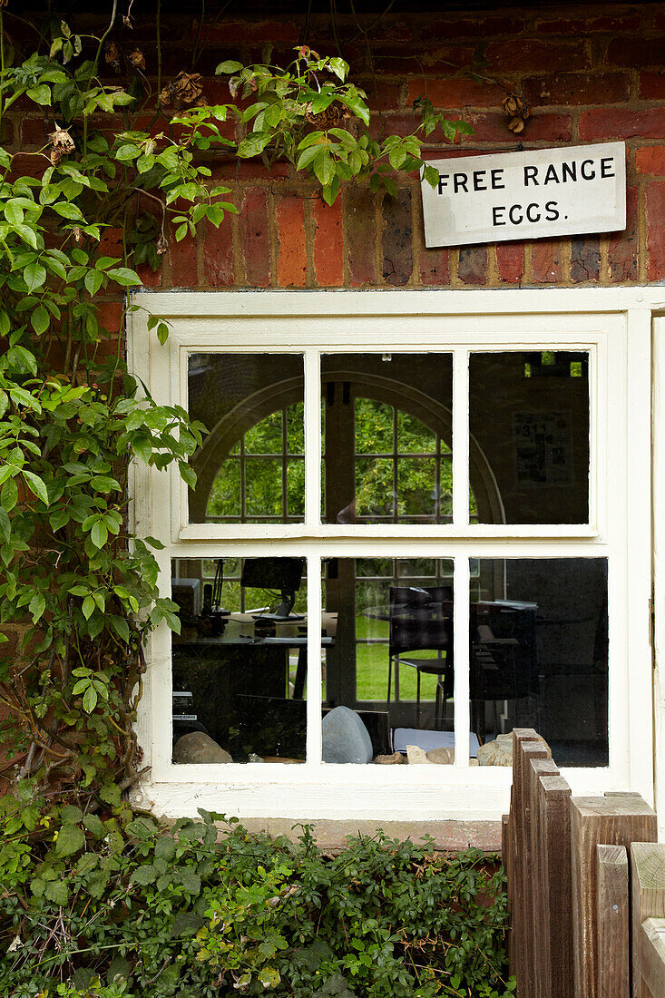 Schild für Eier aus Freilandhaltung über Sprossenfenster eines Hauses in West Sussex, England, UK