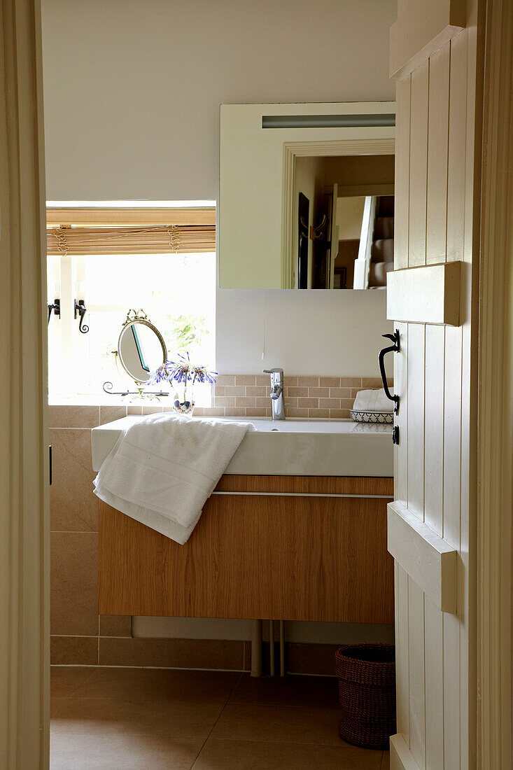 View through bathroom door to wash basin in West Sussex home, England, UK