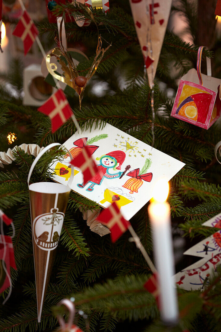 Handgemachte Weihnachtskarte und brennende Kerze mit Ornamenten am Baum in Kopenhagen