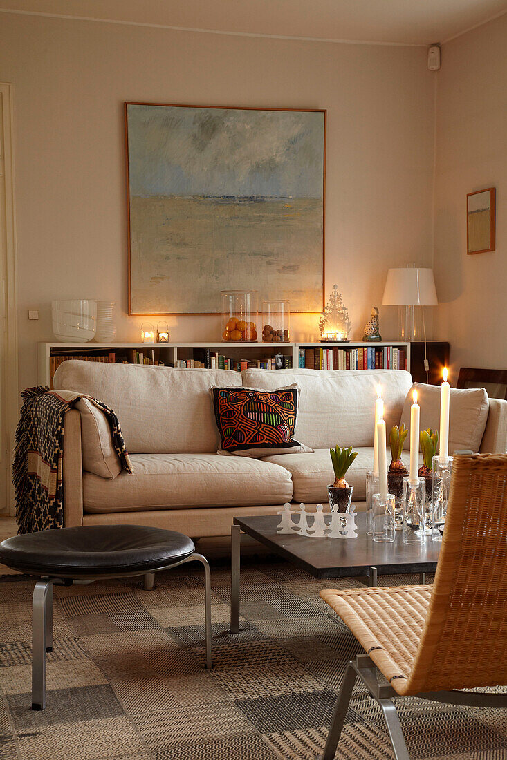 Cremefarbenes Sofa und brennende Kerzen in einem skandinavischen Wohnzimmer