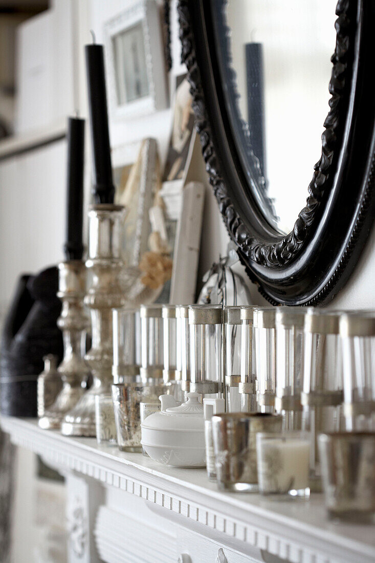 Glassware with black mirror frame above white mantlepiece