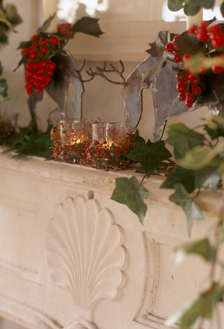 Steinkamin weihnachtlich dekoriert mit Tierfiguren, Stechpalme, Efeu und brennenden Teelichtern