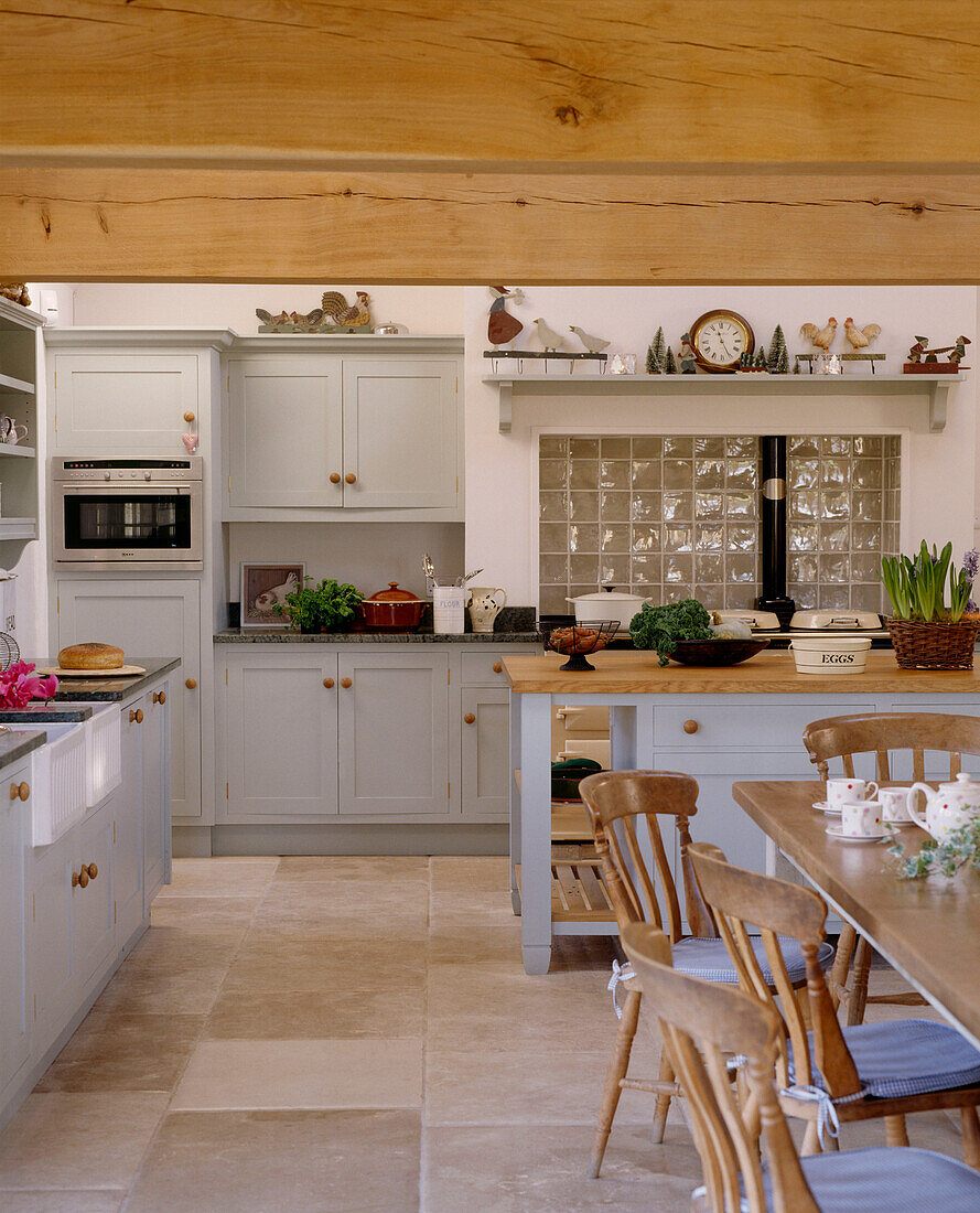 Küche im Landhausstil mit Essbereich, Balkendecke, Steinplattenboden, lackierten Möbel, Kücheninsel, Tisch und Stühlen
