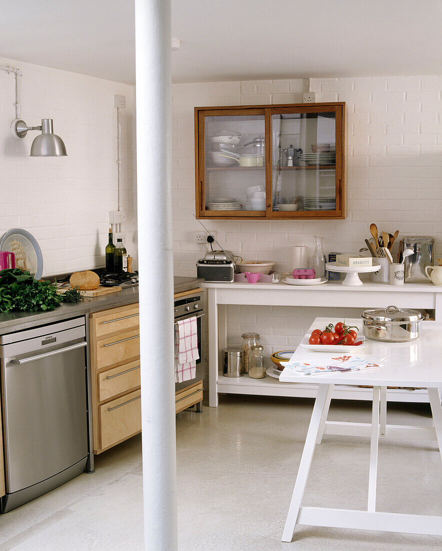 Die Küche ist ein offener Raum mit einem Backofen aus rostfreiem Stahl neben einer hölzernen Küchenzeile und einem an der Wand montierten Schrank über einer bemalten Holzbank