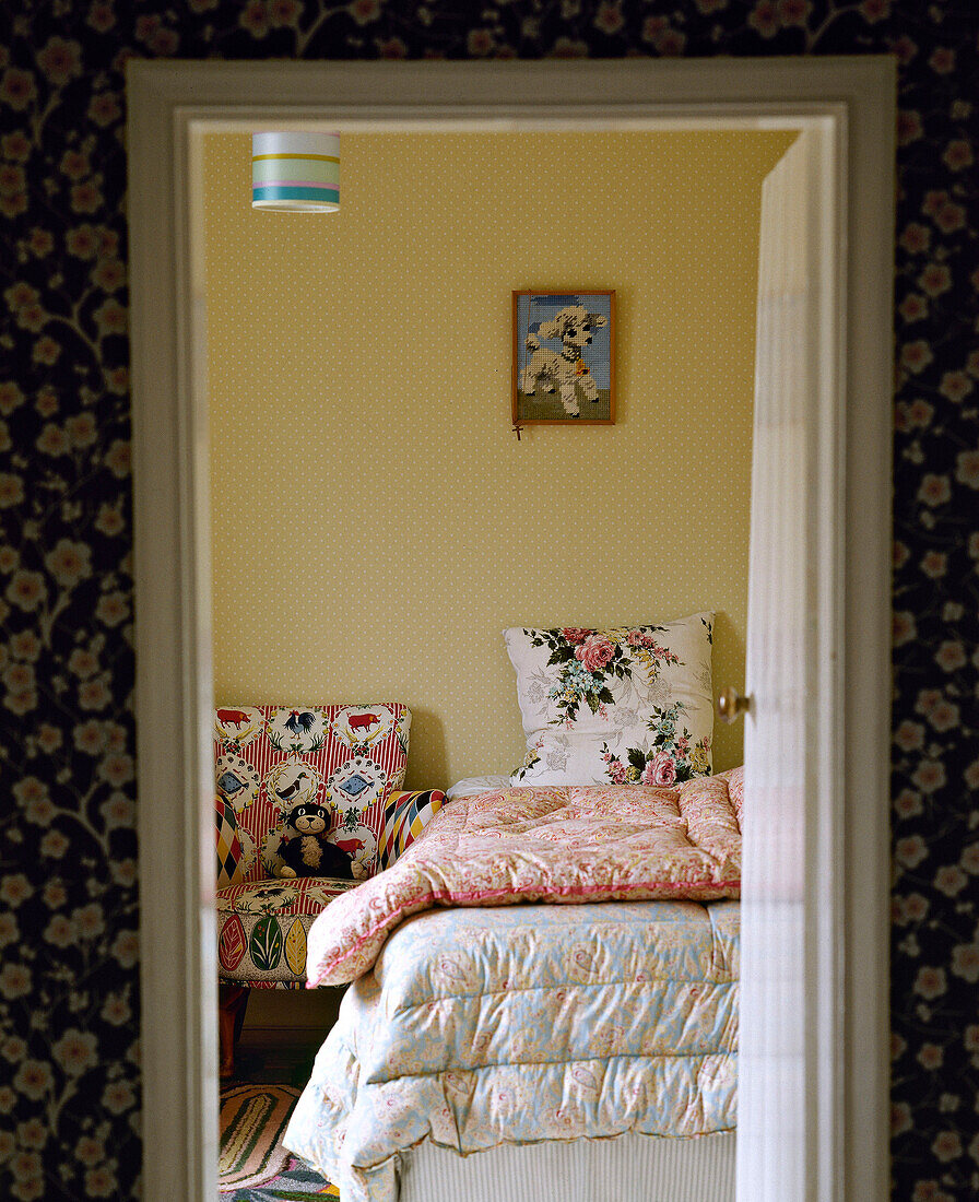 Blick durch geöffnete Tür auf Schlafzimmerbett mit altmodischen Daunendecken