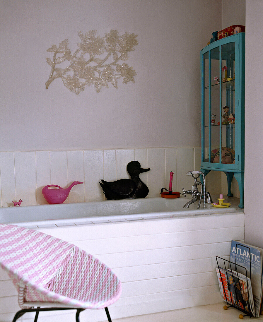 Traditionelles Badezimmer mit weißer Vertäfelung und rosafarbenem geflochtenem Plastikstuhl