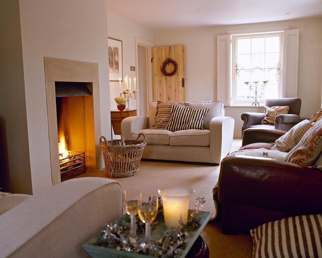 Upholstered furniture in front of open fire in sitting room decorated for Christmas