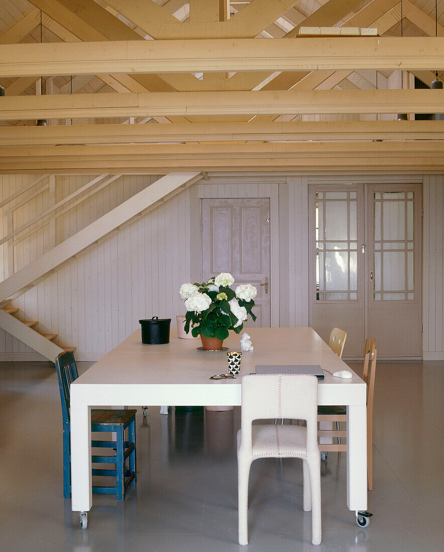 Esszimmer im Landhausstil mit freiliegenden Holzbalken über einem modernen Esstisch