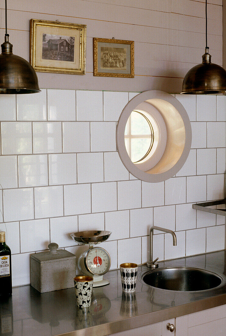 Küche mit weißen Fliesen und einer Spüle, die in eine Arbeitsplatte aus Edelstahl eingebaut ist