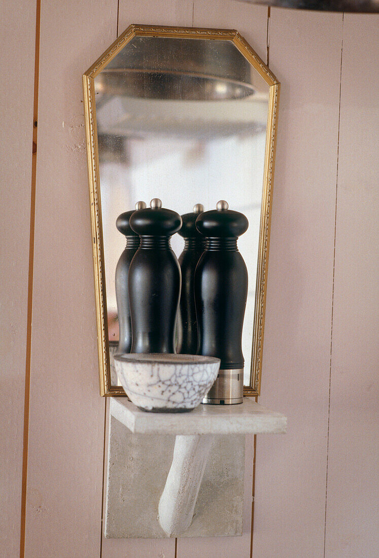Nahaufnahme von schwarzen Salz- und Pfefferstreuern auf einem Sims vor einem kleinen Spiegel
