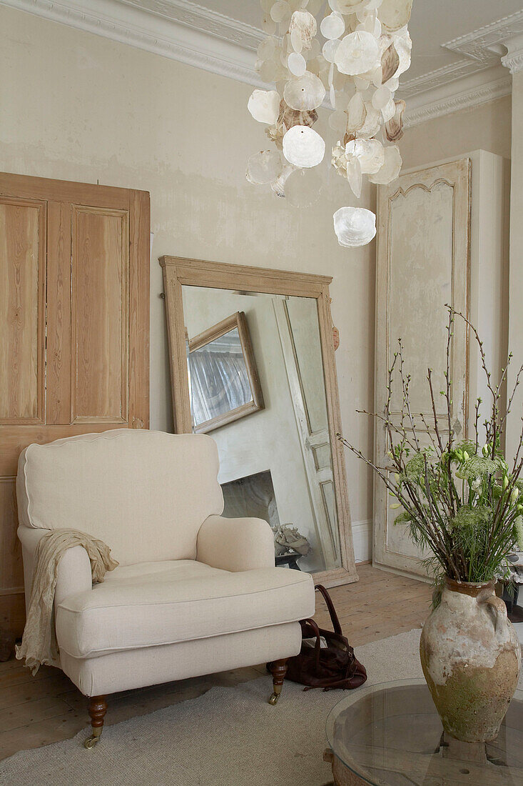 Überdimensionaler Spiegel neben gepolstertem Sessel in neutralem Wohnzimmer