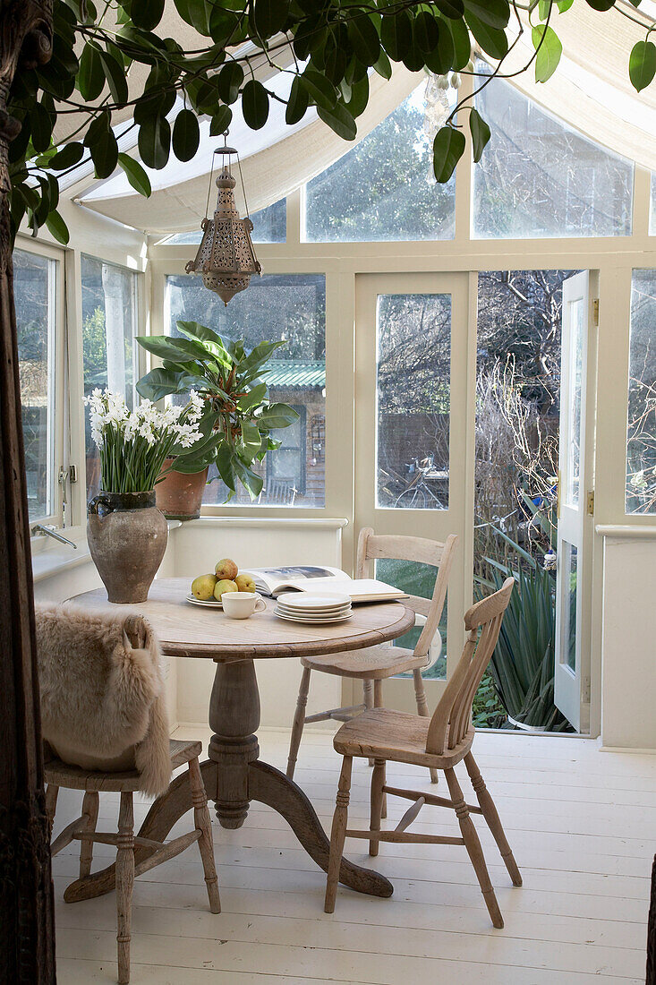 Open book on wooden table with flower arrangement in country style conservatory