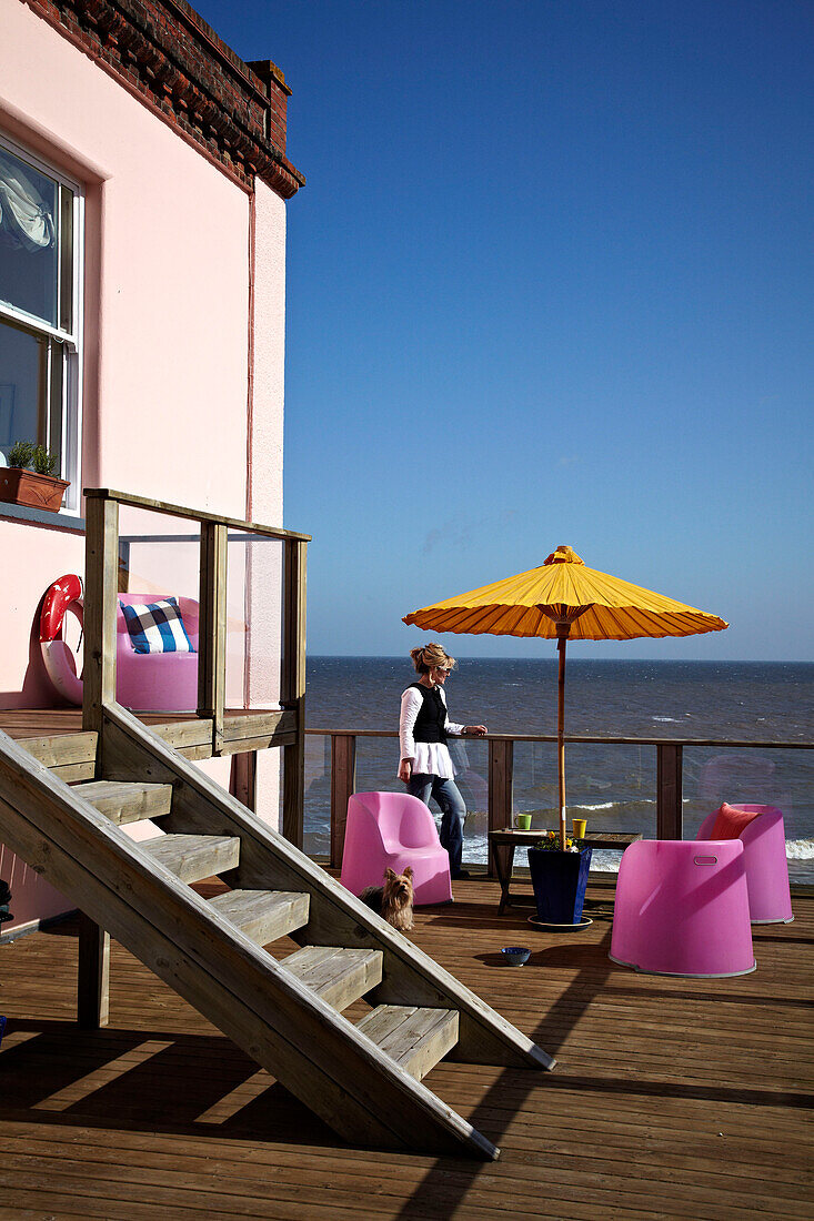 Frau auf der Balkonterrasse eines Strandhauses in Cromer, Norfolk, UK