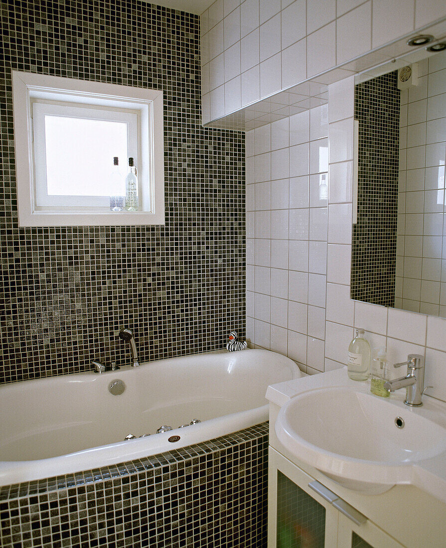 Bathtub next to washbasin in tiled bathroom