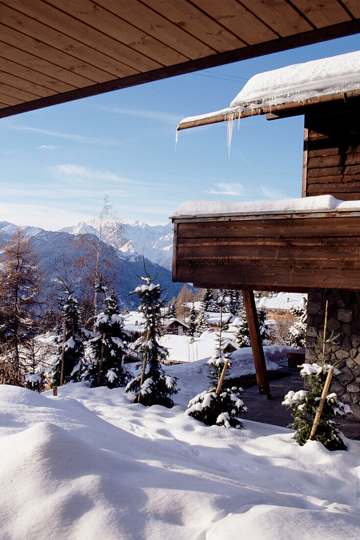 Außenansicht eines traditionellen Schweizer Holzchalets mit Schnee Tannen und Bergen