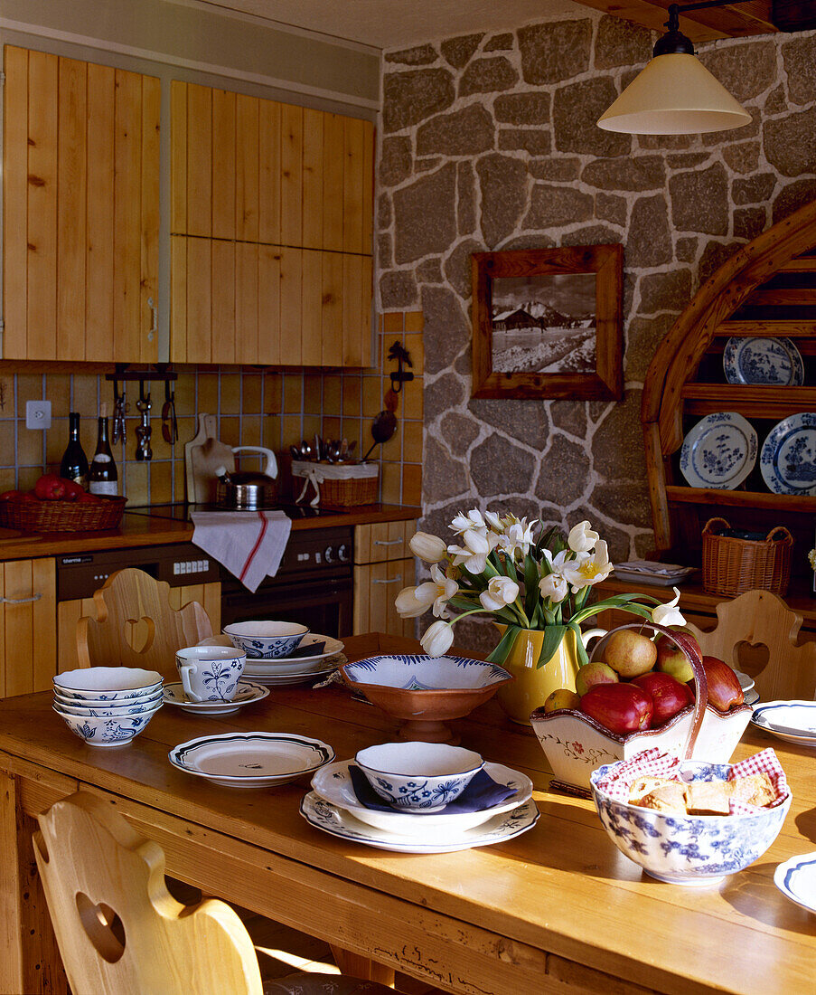 Küche mit Sichtmauerwerk, Schrankelementen aus Kiefernholz und gedecktem Tisch