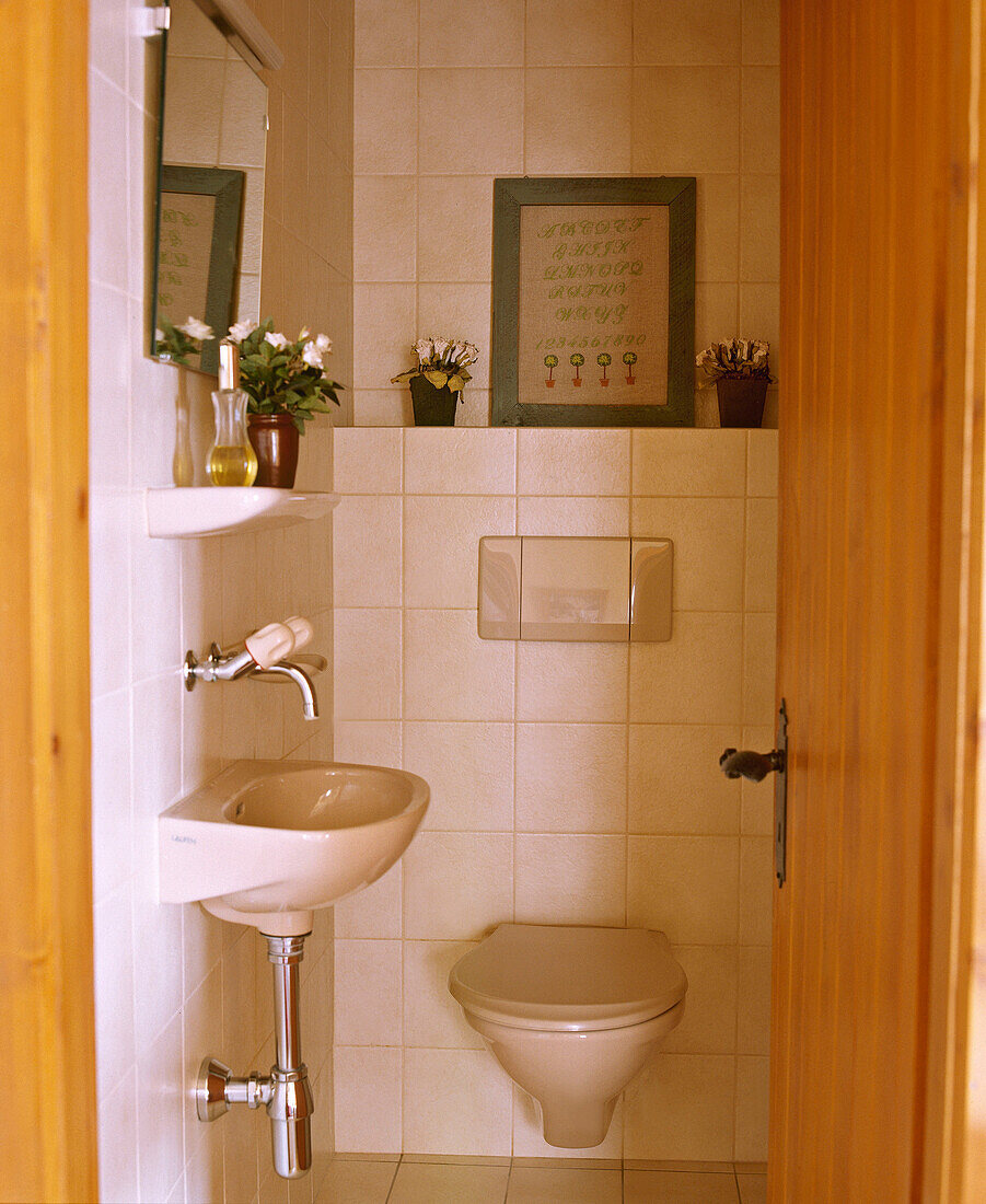 Blick durch die offene Tür zum Badezimmer mit gefliesten Wänden und eingebauter Toilette und Waschbecken
