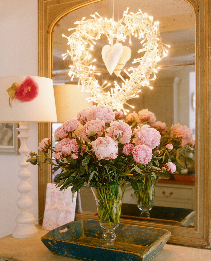Arrangement aus rosa Rosen in Glasvase auf dem Tisch vor Spiegel