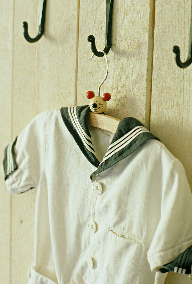 A detail of a child's old fashioned sailor suit hanging from wrought iron hook
