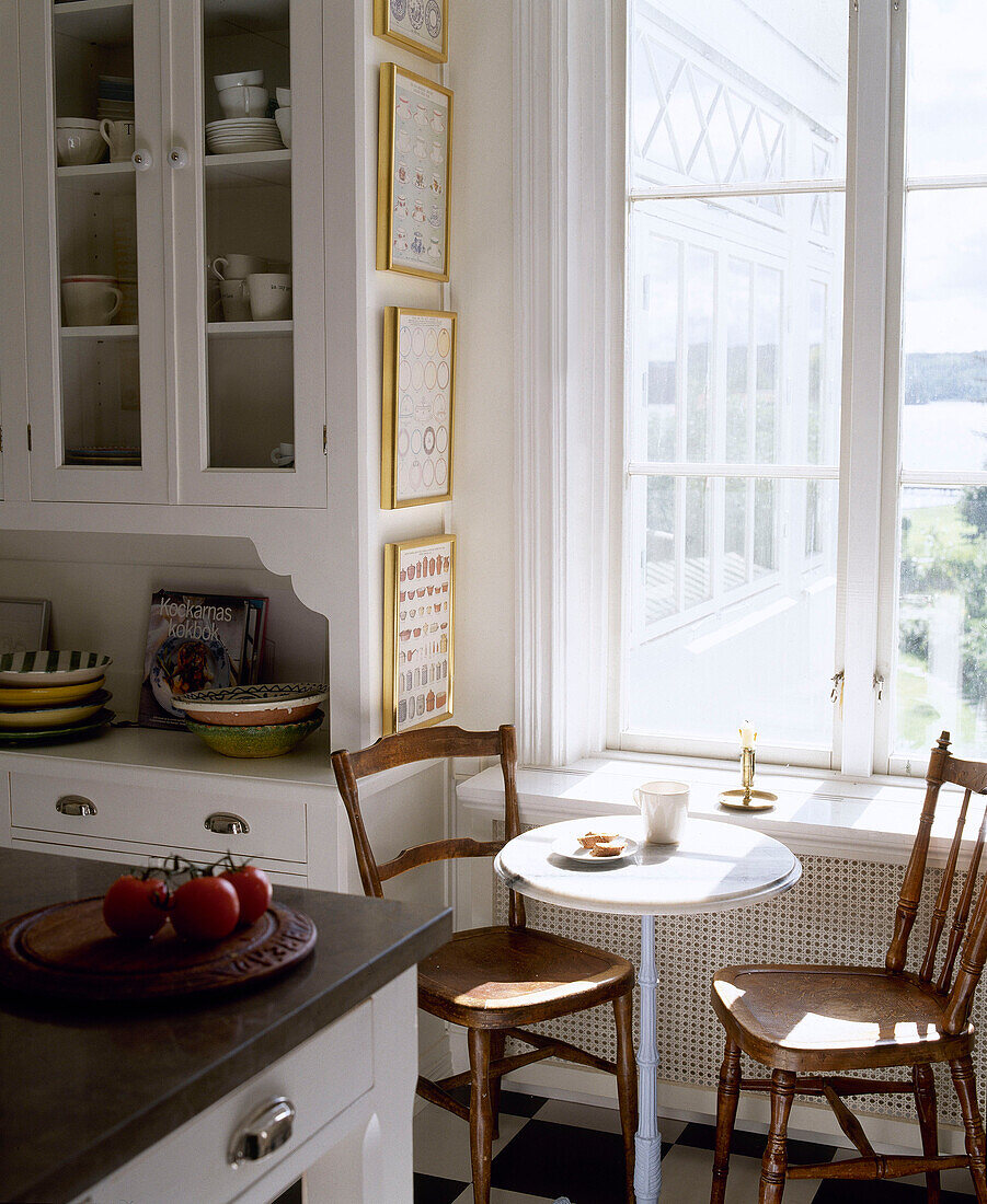 Frühstückstisch und Holzstühle unter dem Fenster in einer Küche im Landhausstil