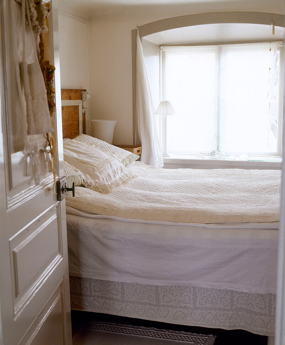 Cremeweißes Schlafzimmer mit Spitzenkissen und Bettdecke
