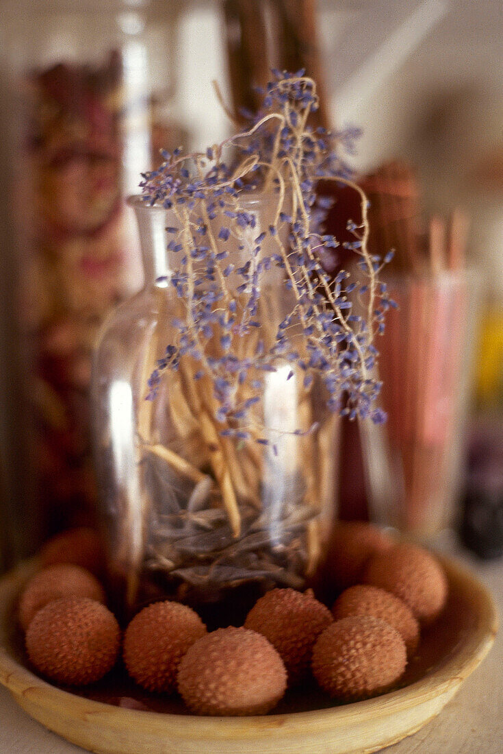 Detail of bowl of lychees glass jar and dried flowers