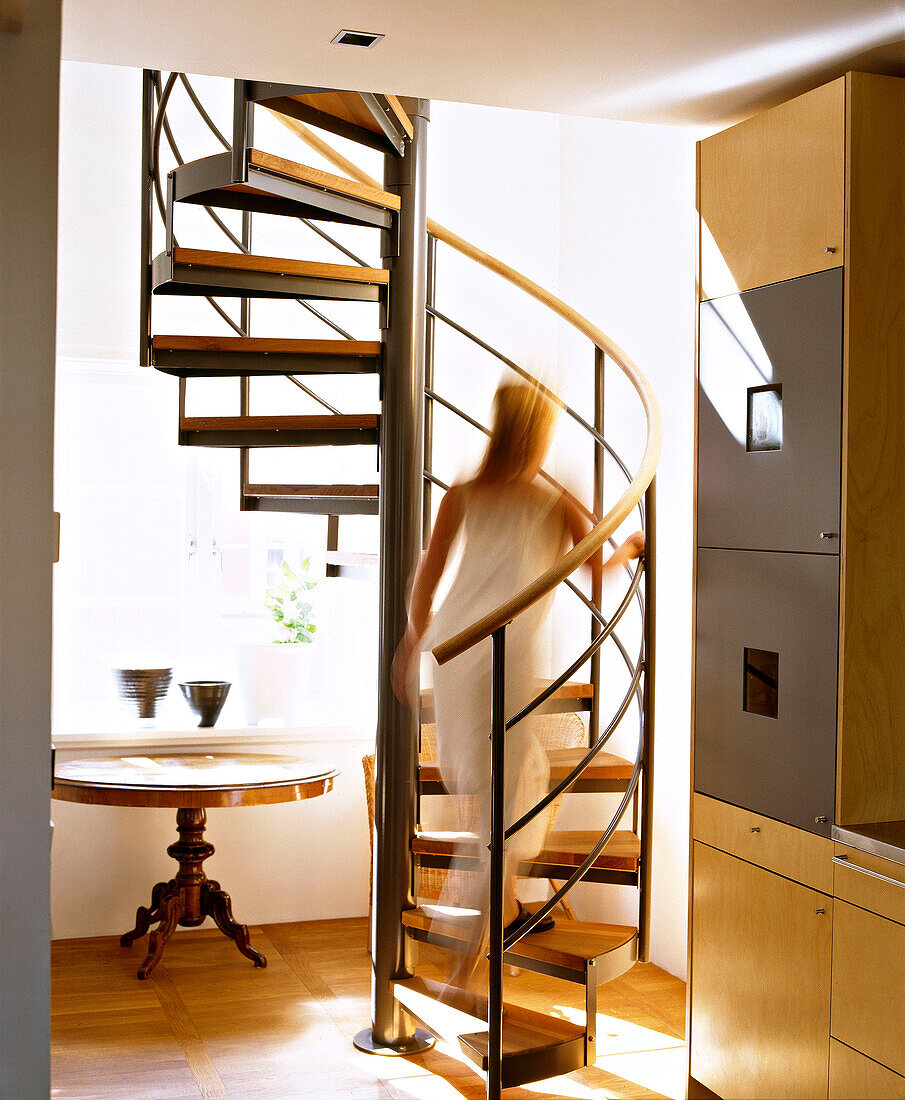 Moderne Spindeltreppe mit Holzstufen, Frau auf der Treppe