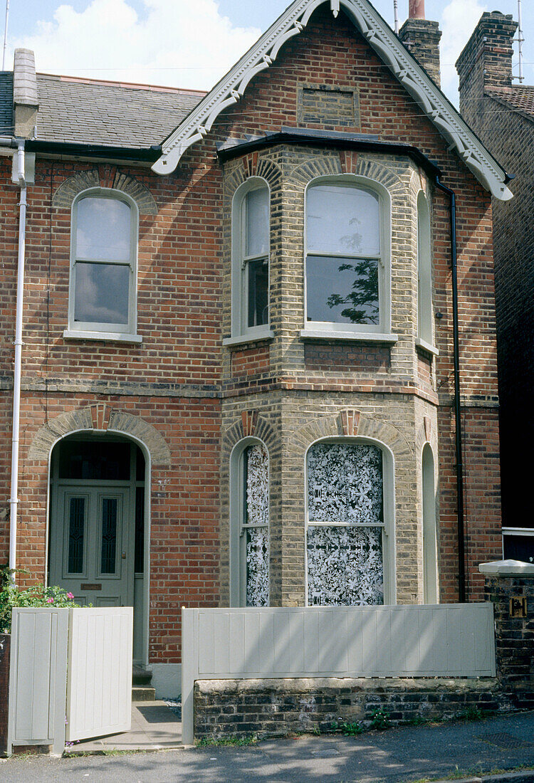 Außenansicht einer gemauerten Doppelhaushälfte mit Schiebefenstern und Eingangstür