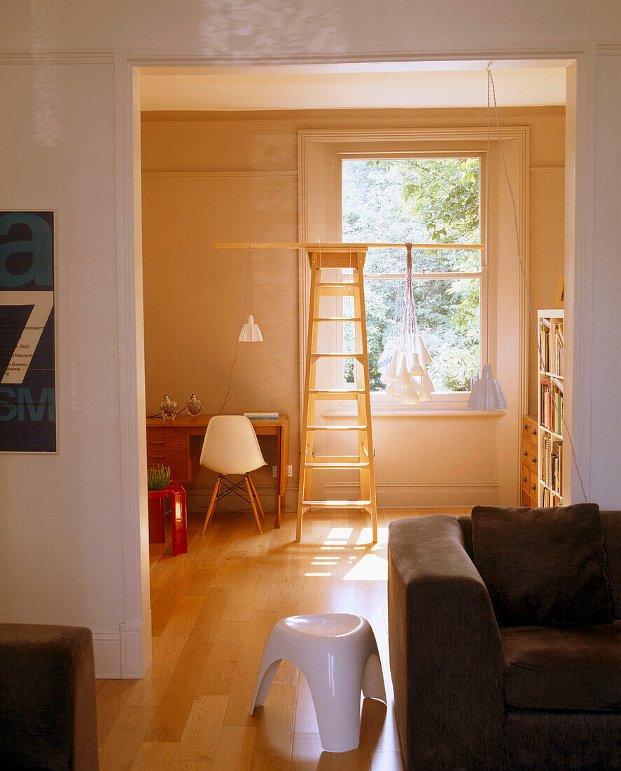 Modernes offenes Wohnzimmer mit Holzboden und Fenster, Retro-Hocker, Schreibtisch, Stufenleiter und Hängelampen