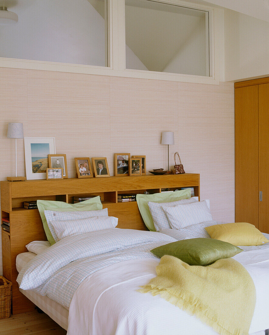 Ein modernes Schlafzimmer mit einem Holzbett mit weißer und hellgrüner Bettwäsche