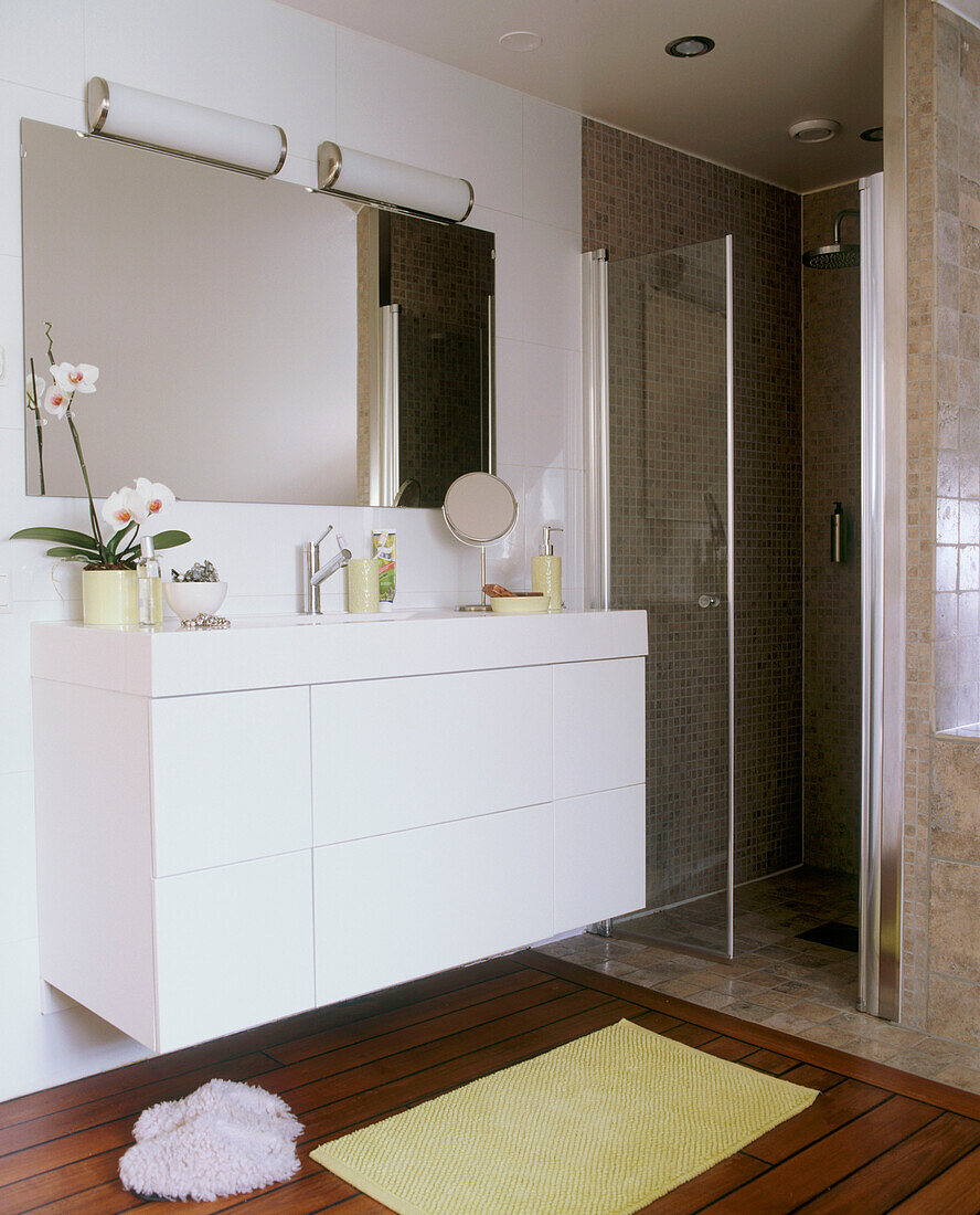 Detail eines modernen Badezimmers mit weißem Waschbecken und gelber Badematte auf einem Boden