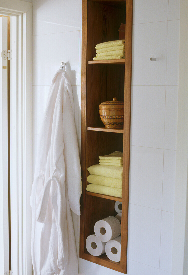 Detail eines Badezimmers mit eingebauten Regalen für Handtücher und Toilettenpapierrollen
