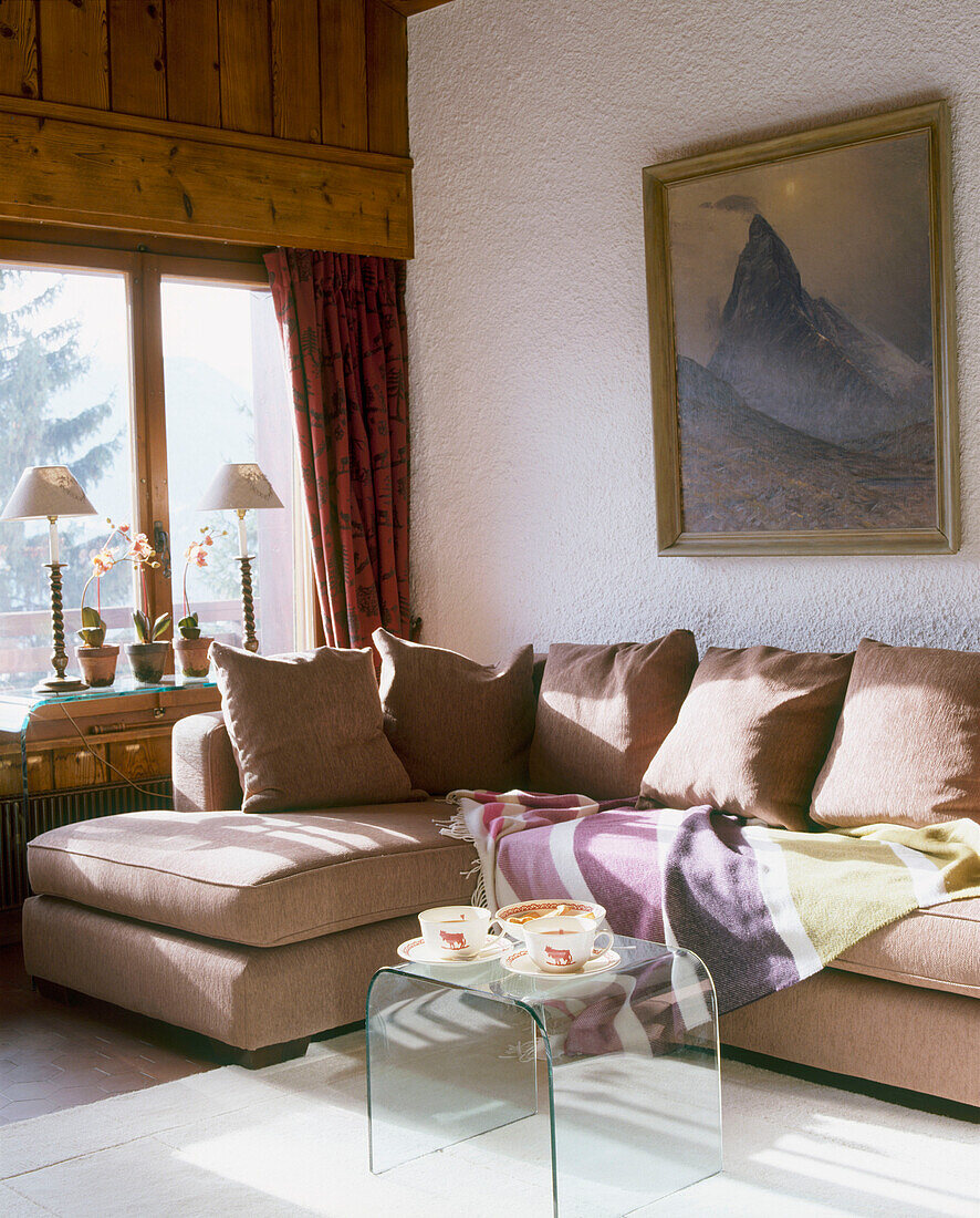 Ein modernes Wohnzimmer im Landhausstil mit Holzvertäfelung, gepolstertem Ecksofa und transparenten Plexiglas-Tischkissen
