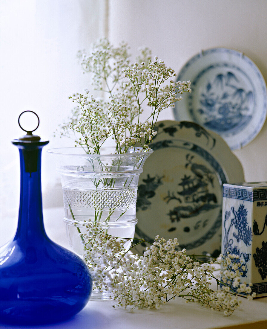 Display of blue glass bottle and china pieces on window sill