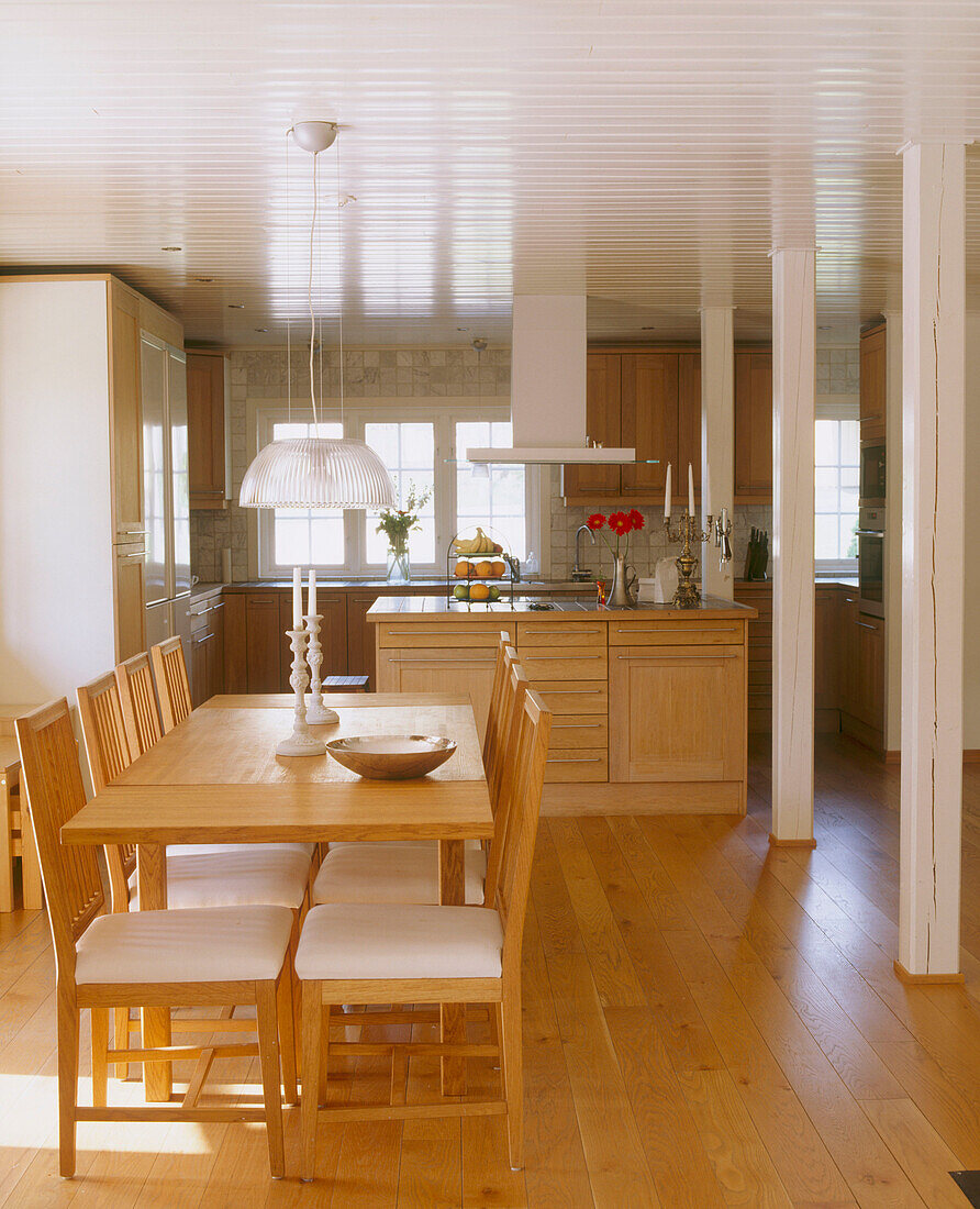 Dining room with a wooden table and chairs in front of an open plan kitchen