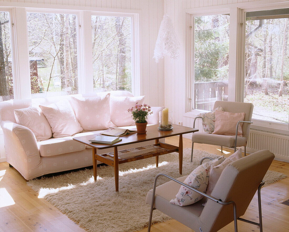 A modern Scandinavian style sitting room with big windows sofa and chairs