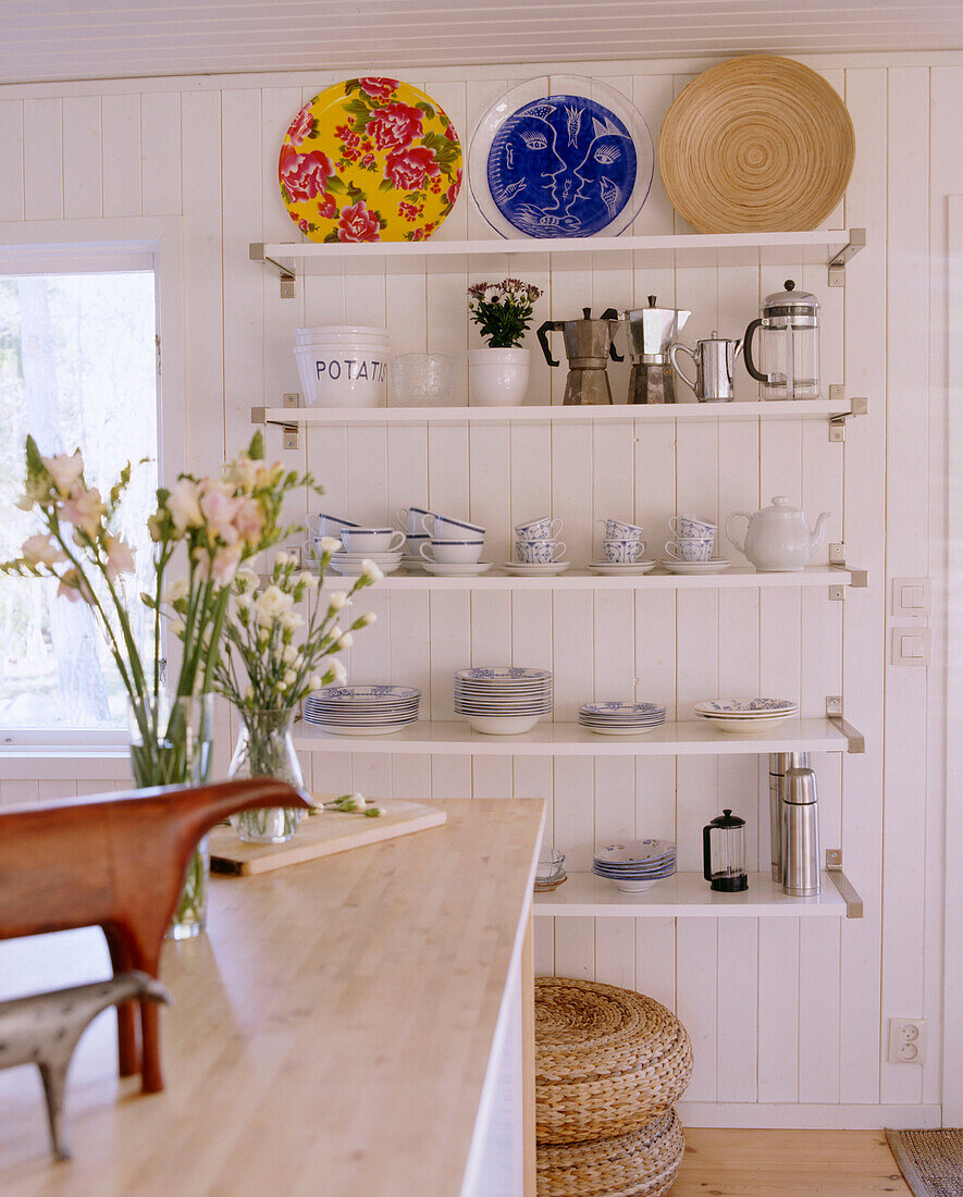 A white country style kitchen central island unit shelves with crockery