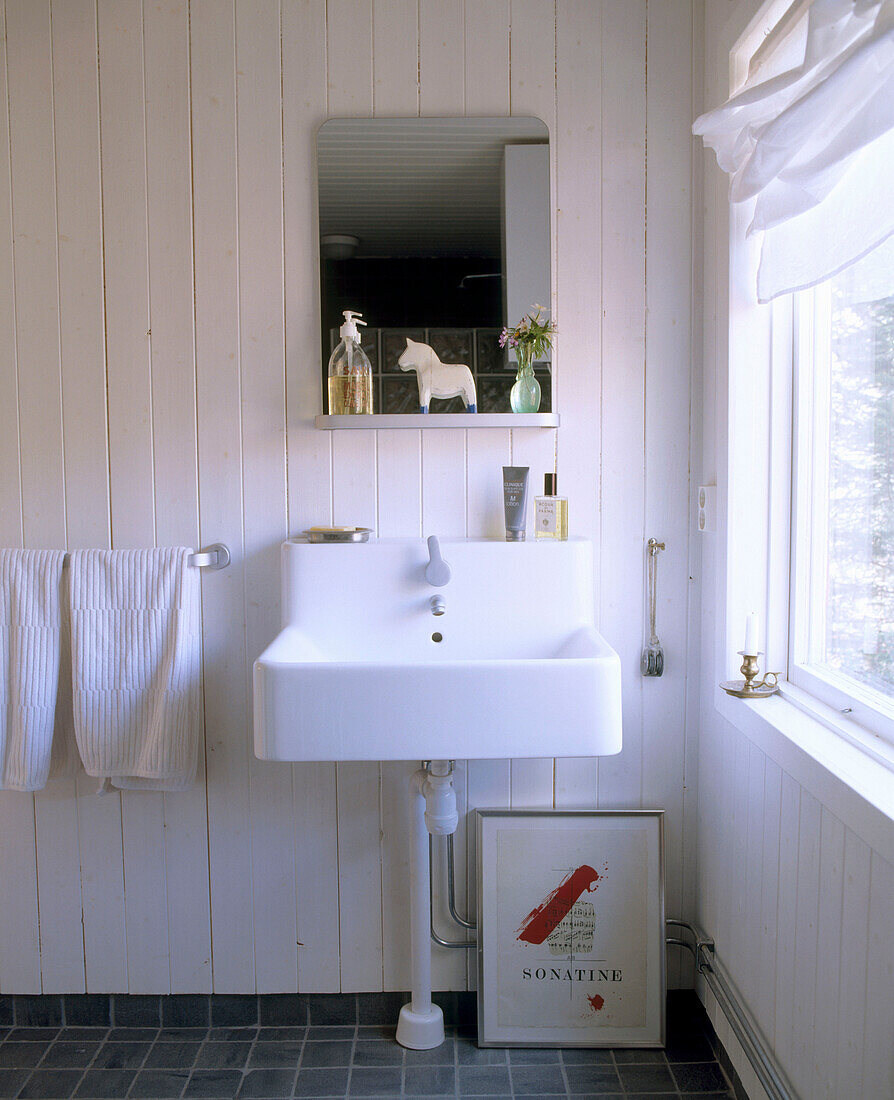 Detail eines Badezimmers im Landhausstil mit weißem Waschbecken und Spiegel